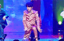 a man in a pink suit is dancing on a stage with other people .