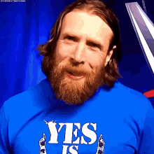 a man with a beard is wearing a blue shirt that says yes is .