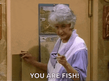a woman with gray hair is pointing at the camera and saying `` you are fish ! ''
