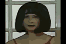 a woman with short black hair is standing in front of a window and looking at the camera .