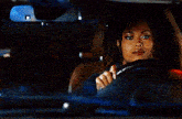 a woman is driving a car at night and looking at the rear view mirror .