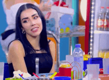 a woman in a black dress is sitting at a table