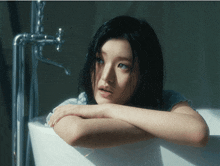 a woman in a bathtub with her head resting on her arm