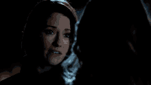a woman is crying while looking at another woman in the dark
