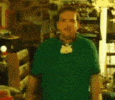 a man wearing a green shirt with a cat necklace around his neck .