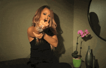 a woman in a black dress is giving the middle finger in front of a pink flower