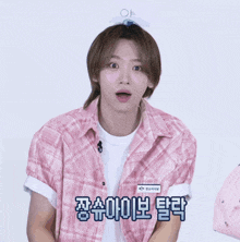 a young man wearing a pink plaid shirt and a white t-shirt with korean writing