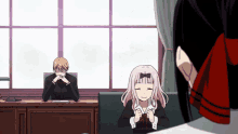 a man sits at a desk with his head in his hands while a girl sits in front of him smiling