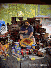 a man sits in a chair surrounded by fireworks including a can that says ' trick ' on it