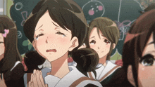 a girl is crying in front of a blackboard with a drawing of a cherry on it