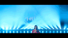 a woman singing into a microphone on a stage with a lot of blue lights