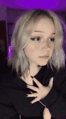 a girl with blonde hair and black nails is wearing a black sweater