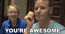 a man and a boy are sitting next to each other and the boy is smiling while the man says you 're awesome .