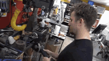 a man using a grinder in a workshop with the website www.thehacksmith.ca in the corner