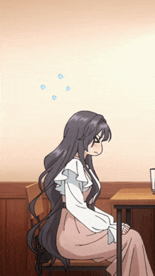 a girl with long hair sits at a table with a glass of water