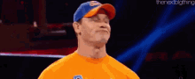 a man wearing a blue and orange hat and an orange shirt is standing on a stage .