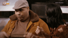 a man wearing a hat is talking to a woman with the gnl express logo in the corner