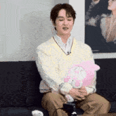 a man is sitting on a couch holding a stuffed animal