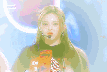 a woman with long blonde hair is wearing a green shirt and a microphone on her head .