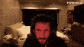 a man with a beard is wearing headphones and a red light is shining on his face .