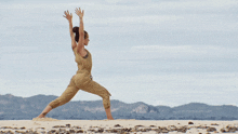 a woman is practicing yoga on a beach with her arms outstretched