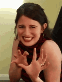 a woman with a ring on her finger is smiling and waving her hands