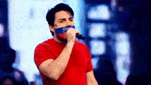 a man in a red shirt singing into a microphone with a venezuelan flag on his face