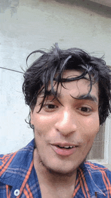 a man in a plaid shirt is making a funny face with his mouth open