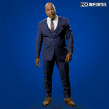 a man in a suit is dancing in front of a blue background that says " fox deportes "