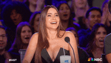 a woman sitting in front of a microphone with a nbc logo in the background