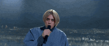 a young man singing into a microphone in front of a city