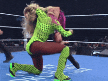 a female wrestler in a neon green outfit is kneeling down