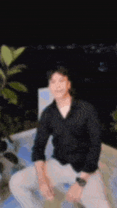a blurry picture of a man in a black shirt sitting on a ledge .