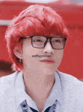 a young man with red hair wearing glasses and earrings