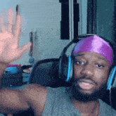 a man wearing headphones and a purple headband is waving