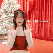 a girl in front of a christmas tree with the words merry christmas