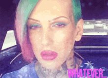 a woman with green and pink hair is wearing a blue shirt with the word whatever on it