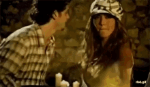 a man and a woman are standing next to each other and looking at each other . the woman is wearing a hat .