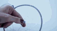 a woman is making a dream catcher with beads and yarn .