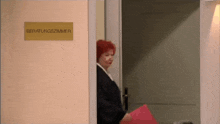 a woman with red hair stands in front of a door that says beratungszimmer