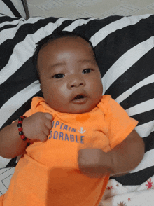 a baby wearing an orange shirt that says " captain doable "