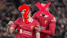 two soccer players wearing red uniforms with the word standard chartered on the front