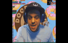 a man wearing headphones playing a video game with a donut in the background