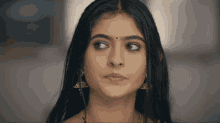 a woman with a red bindi on her forehead looks to the side