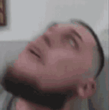 a man with a beard is laying on a couch with his head up .