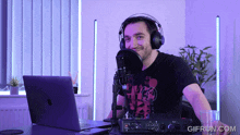 a man wearing headphones sitting in front of a microphone with a gifrun.com logo on the bottom right