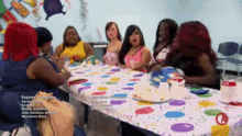 a group of women sitting around a table with plates of food