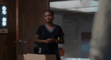 a woman in a scrub top is standing in front of a door in a hospital .
