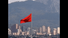 a red flag is flying in front of a city