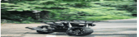 a motorcycle is driving down a road next to a tree .